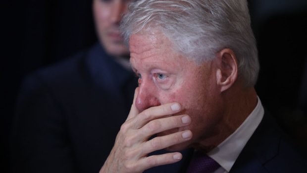 Bill Clinton listens as his wife gives her concession speech.