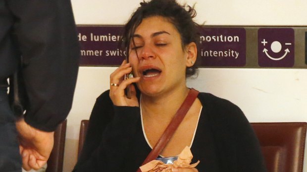 A relative of the victims reacts as she makes a phone call at Charles de Gaulle Airport outside Paris.