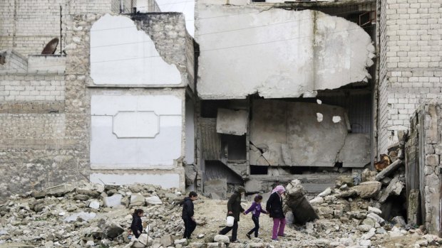 Children walk through the debris of a damaged building in Aleppo.