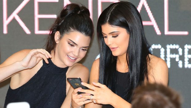 Kendall Jenner and Kylie Jenner look at their mobile phones as they arrive at Chadstone.