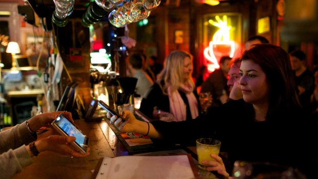 Sophie Brown pays for her drink with bitcoins on her phone at the Old Fitzroy.