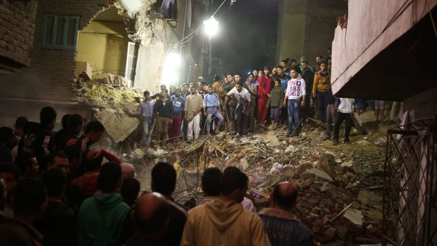 Cairo residents stand on the remains of the collapsed building.