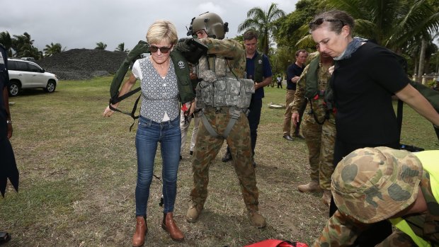 A crewman helps Foreign Affairs Minister Julie Bishop put on her lifejacket for a helicopter ride to Rakiraki during her visit to areas affected by Tropical Cyclone Winston. 
