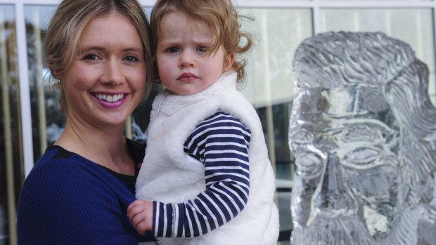 Michelle Cooper, of Weston Creek, with her daughter Jade, 18 months, rugged up beside a fleeting ice sculpture of Sir Henry Parkes, who was born 200 years ago.