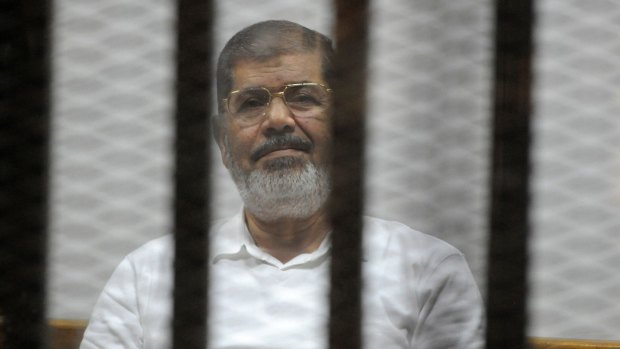 Deposed Egyptian president Mohamed Morsi sits behind bars during a trial in Cairo in early November.