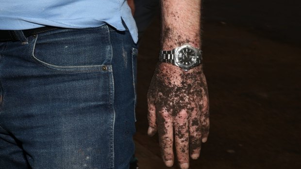 Prime Minister Tony Abbott's hands get dirty during gardening as he assists in the community hall upgrade in the Injinoo community.