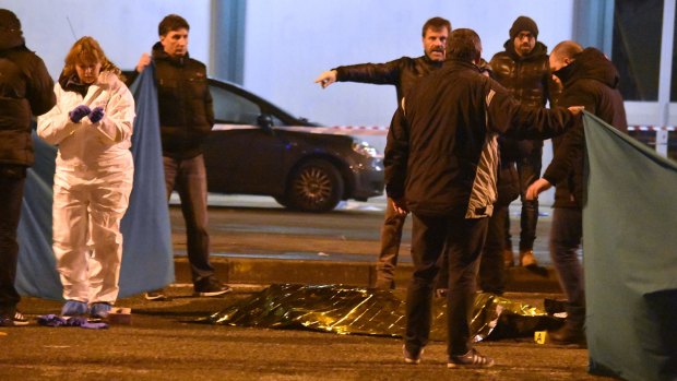 A body is covered in a blanket as Italian police cordon off an area after a shootout between police and a man believed to be Anis Amri.