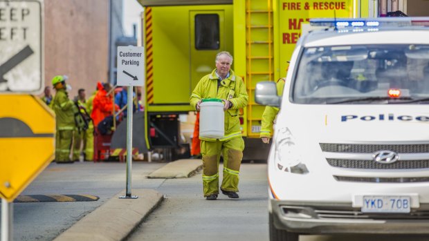 An ACT Fire & Rescue member hands over a suspicious powder found inside the Fyshwick Mail Centre to police.