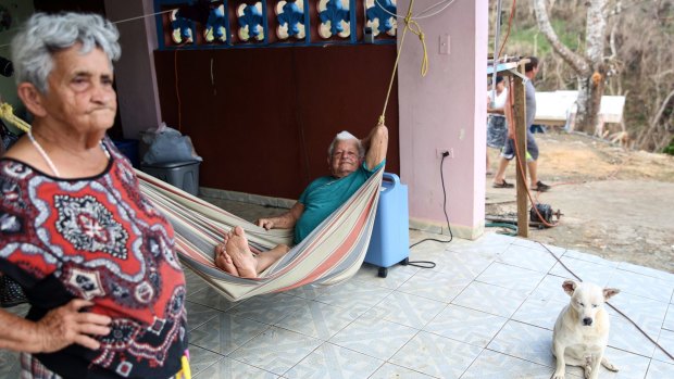 A resident sits in a hammock while using an oxygen machine hooked up to a power outlet connected to a generator.