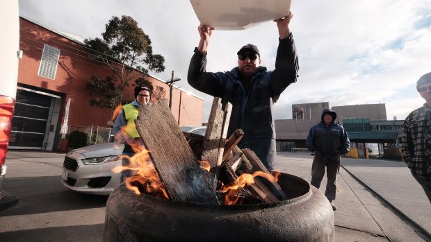 Sacked workers try to keep warm on the picket line.