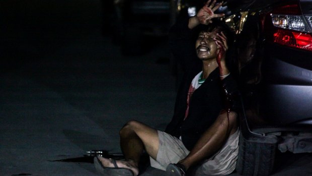 Francisco Maneja, bleeding from gun shot wounds, raises his hands to ask for help in Manila.
