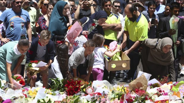 People lay flowers to pay respect to the shooting victims at a makeshift memorial at Martin Place in Sydney.