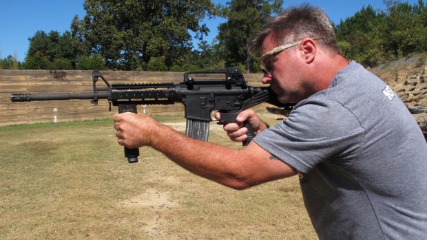 Shooting instructor Frankie McRae aims an AR-15 rifle fitted with a "bump stock" at his 37 PSR Gun Club in North Carolina. 