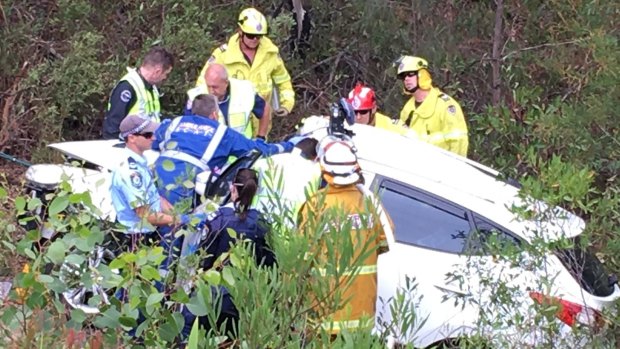 Emergency services officers work to cut Samuel Lethbridge from the wreck of his car.