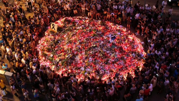 People pay respects at a memorial tribute of flowers, messages and candles to the victims on Barcelona's historic Las Ramblas promenade.