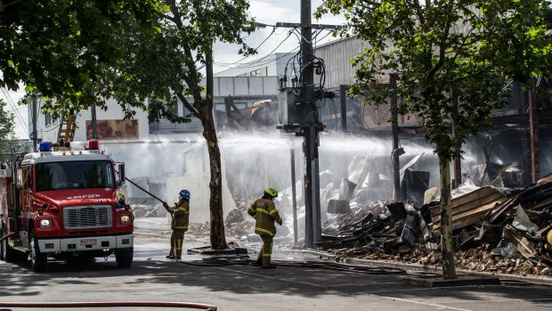 Fire crews continue to hose-down smoldering remains of the market on Wednesday morning.