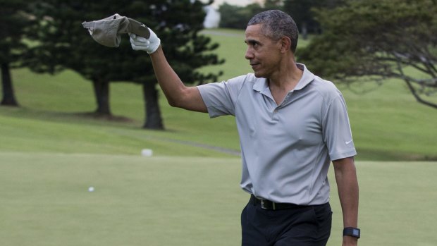 US President Barack Obama tips his cap to a crowd of onlookers after hitting a long chip shot on the 18th hole during a round of golf at Mid-Pacific Country Club.