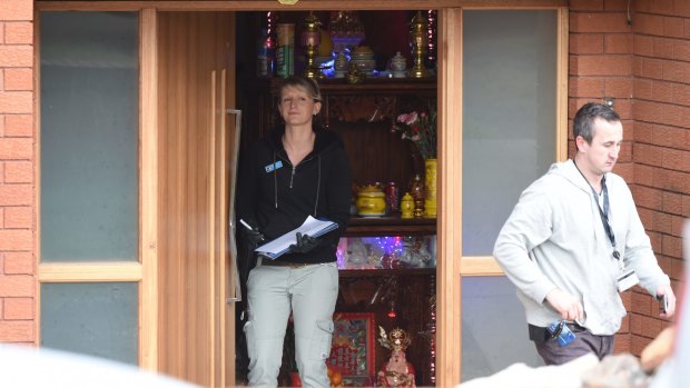 Police search a house, which appears to have a Buddhist shrine inside the front door, in Cabramatta. 