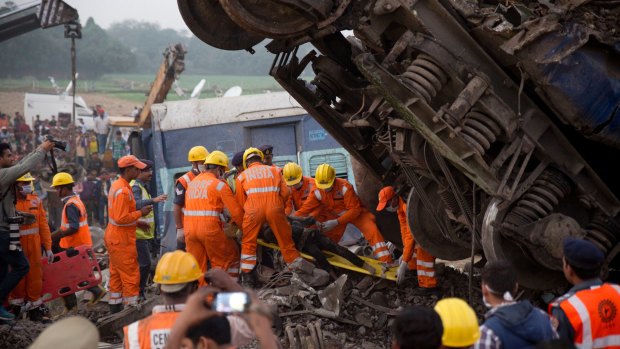 Rescuers pull out a body from the debris of an overnight passenger train disaster in India on Sunday.
