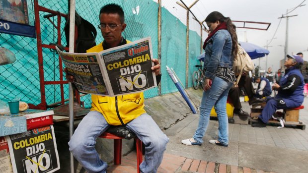 A man reads a newspaper with the headline that reads in Spanish: "Colombia said No" in Bogota