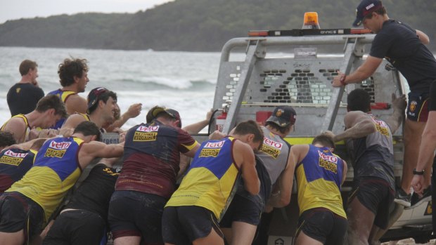 Gruelling: Brisbane Lions players push a truck out of sand on their pre-season camp.