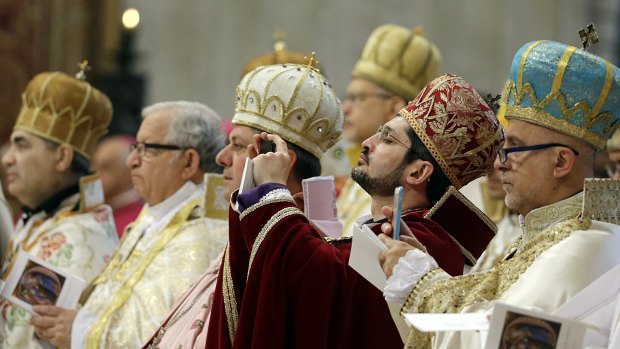 Prelates take photos as Pope Francis celebrates an Armenian-Rite Mass in the Vatican on Sunday.