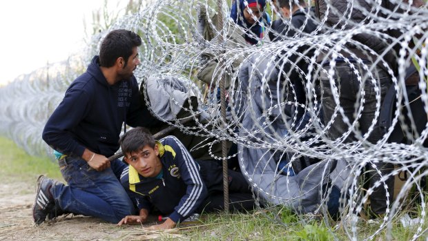 Syrian migrants cross under a fence into Hungary at the border with Serbia, near Roszke on Wednesday.