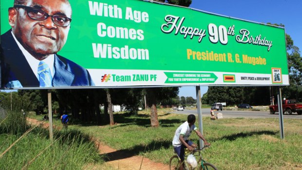 A man cycles beneath a year-old billboard wishing Mr Mugabe a happy 90th birthday in Harare.  