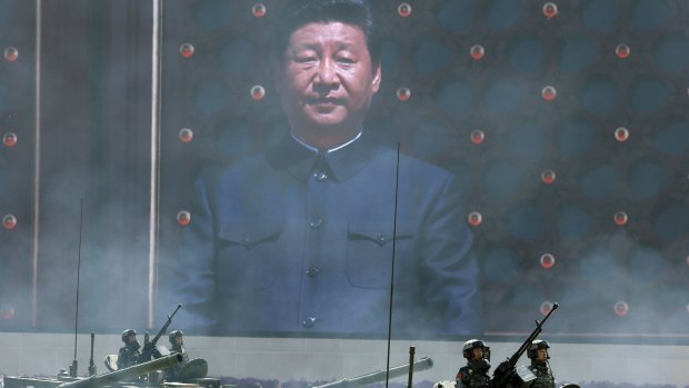 Chinese President Xi Jinping is displayed on a big screen as Chinese battle tanks parade  below.