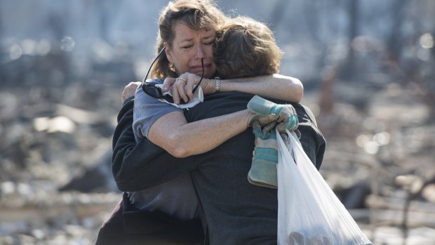Casey Snow and Susan Taylor Fellbaum embrace as they look through their burned homes in Santa Rosa