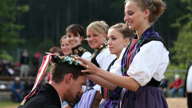 A maid of honour crowns the winner Kilian Wenger with a wreath after the Alpine Wrestling Festival.