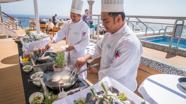 Viking Star chefs cooking fresh Norwegian fish on the terrace of the World Cafe.