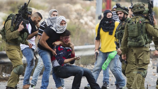 Undercover Israeli police officers and Israeli soldiers detain a wounded Palestinian demonstrator, being pulled up, during clashes near Ramallah, West Bank.