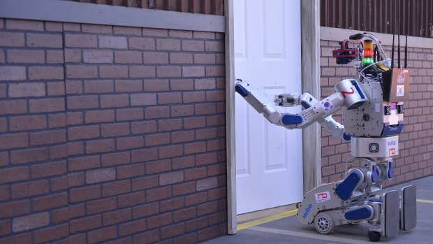 The robot DRC-HUBO stoops to conquer a door on its way to winning the DARPA Robotics Challenge.