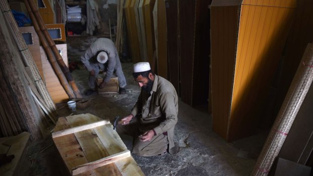 Dreadful boom time ... Pakistani carpenters make coffins at a workshop in Peshawar.