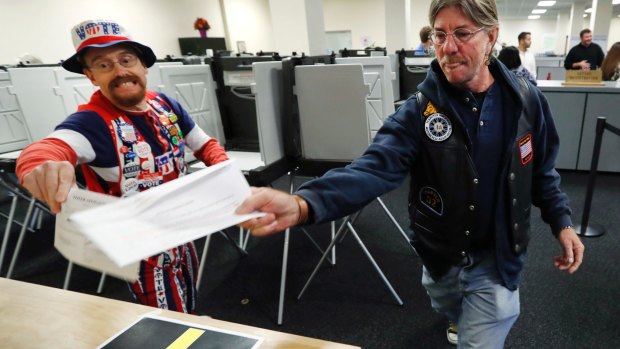 John Olsen, left, and Mark Cooper, race to be the first to get their ballot in the box on the first day of early voting in Des Moines, Iowa.