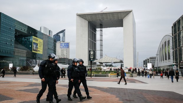 Armed police officers walk through La Defense business district in front of the Grande Arche in Paris on Monday.