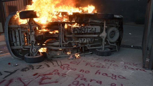 A car burns next to graffiti reading "If there is no justice for the people, shall be no peace for the government" during a protest demanding for justice in the case of the 43 missing students, outside the State Government headquarters in Chilpancingo, Guerrero State