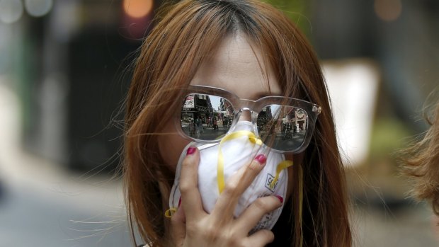 Myeongdong Shopping district is reflected in the sunglasses of a tourist wearing a mask to prevent contracting MERS in Seoul.