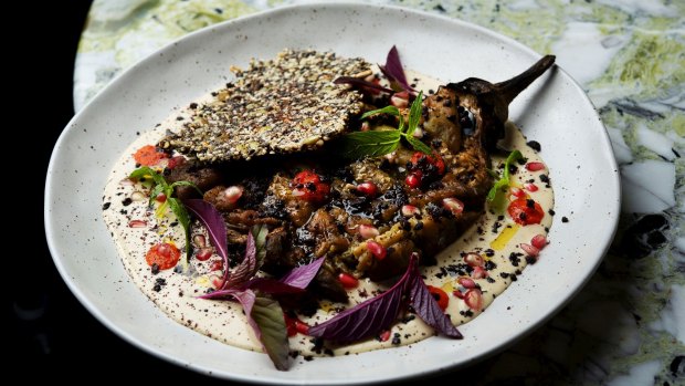 Fire-roasted eggplant, daubed with tahini, and dappled with fermented chilli, baby leaves and olives.