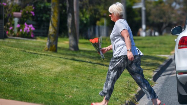 A well-wisher brings flowers to the home of the elderly Rosebud couple on Friday.