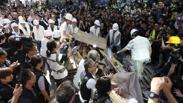 Protesters and media gather round as work teams remove the makeshift barricades.