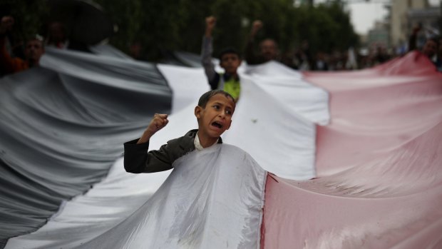 A boy chants slogans through a gap in a national flag raised by Shiite rebels during a protest against Saudi-led airstrikes in Sanaa, Yemen, on April 15.