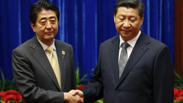 Japanese Prime Minister Shinzo Abe (left) and Chinese President Xi Jinping shake hands.