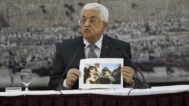 Palestinian President Mahmoud Abbas shows a picture of Palestinian minister Ziad Abu Ein as he is grabbed by an Israeli border policeman.