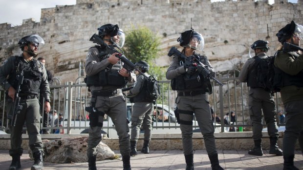 Israeli police officers stand guard as Palestinian women protest outside the Damascus Gate in Jerusalem Old City.