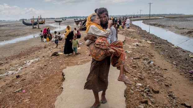 A Rohingya Muslim man Abdul Kareem walks towards a refugee camp carrying his mother Alima Khatoon after crossing over from Myanmar into Bangladesh.