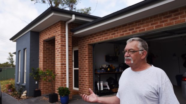 Dick Hurst in front of his new home almost two years after a bushfire destroyed many of the houses in Winmalee.