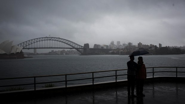 Tourists huddle under an umbrella as rain hits Sydney Harbour on Wednesday.