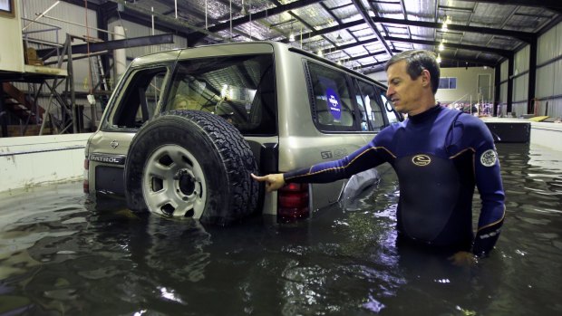 UNSW researcher Grantley Smith moves a four-wheel drive with his fingertip after it begins to float in a floodwater simulation.